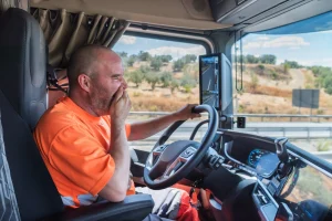 Foto van een vrachtwagenchauffeur die last heeft van mentale druk en vermoeid is